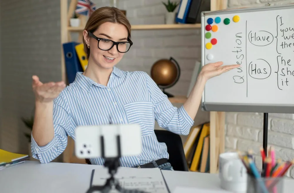 Teacher filming a lesson at a whiteboard with her phone